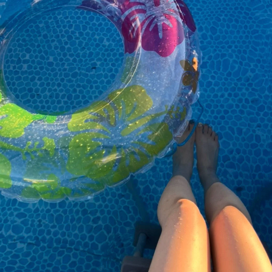 プールの水面に浮かぶ足と浮き輪