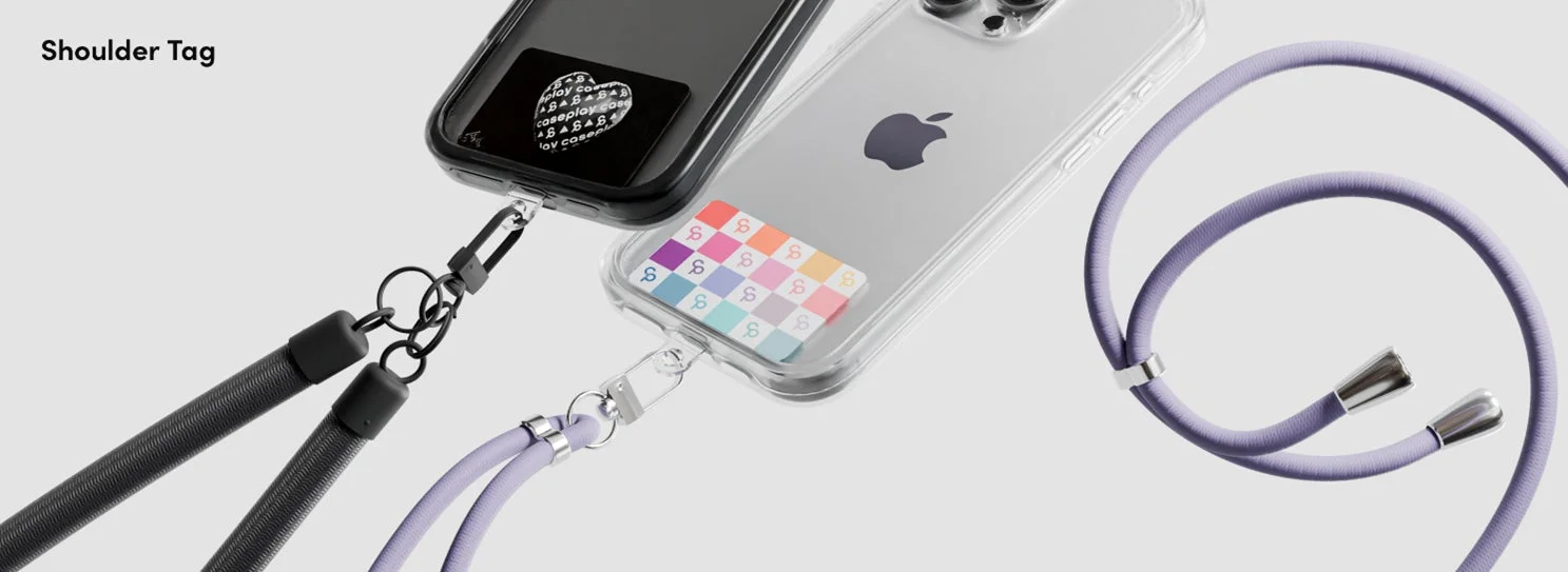 2台のiPhoneがショルダーストラップ付きのスマホケースに装着されている様子。1台はクリアケースにカラフルなSマークのカードが、もう1台は黒いケースに「Joy Coral」と書かれたカードが入っている。ストラップは黒とラベンダー色で、肩掛けスタイルを提案している。