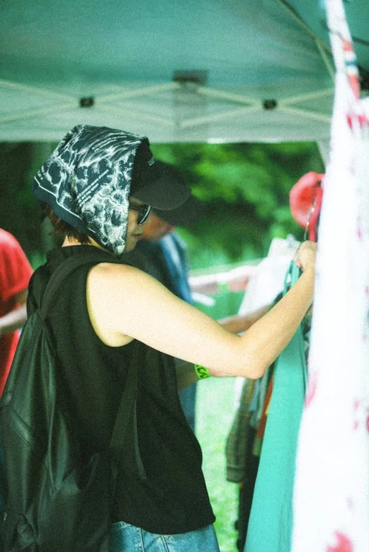 屋外マーケットで衣類を選ぶ人