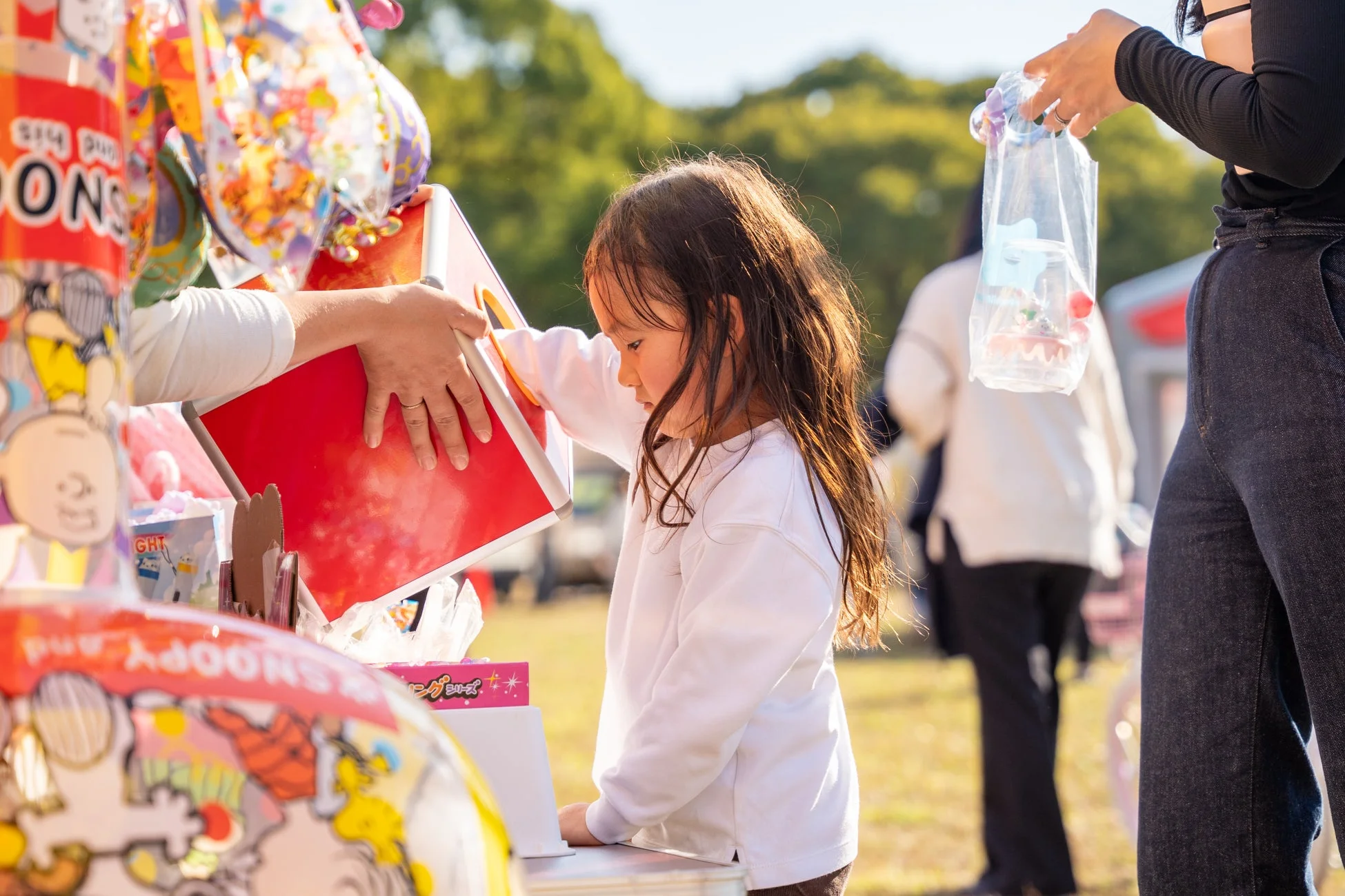 キャラクターグッズが並ぶ屋台を見る少女