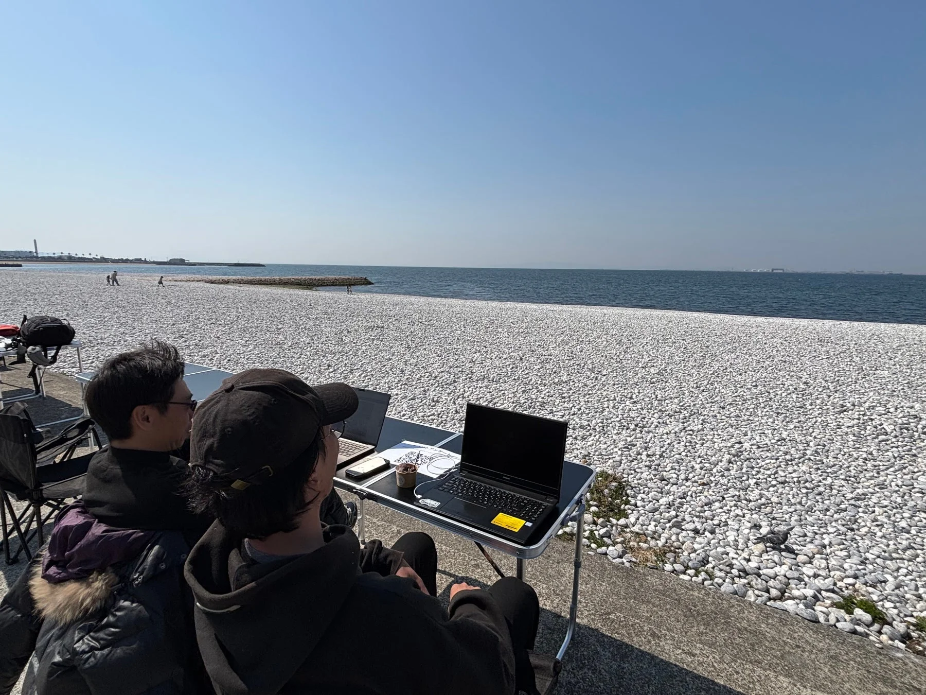 ビーチでPC作業する男性