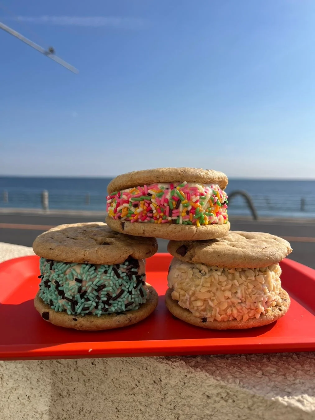 カラフルなスプリンクルやトッピングが施された3つのアイスクリームサンド