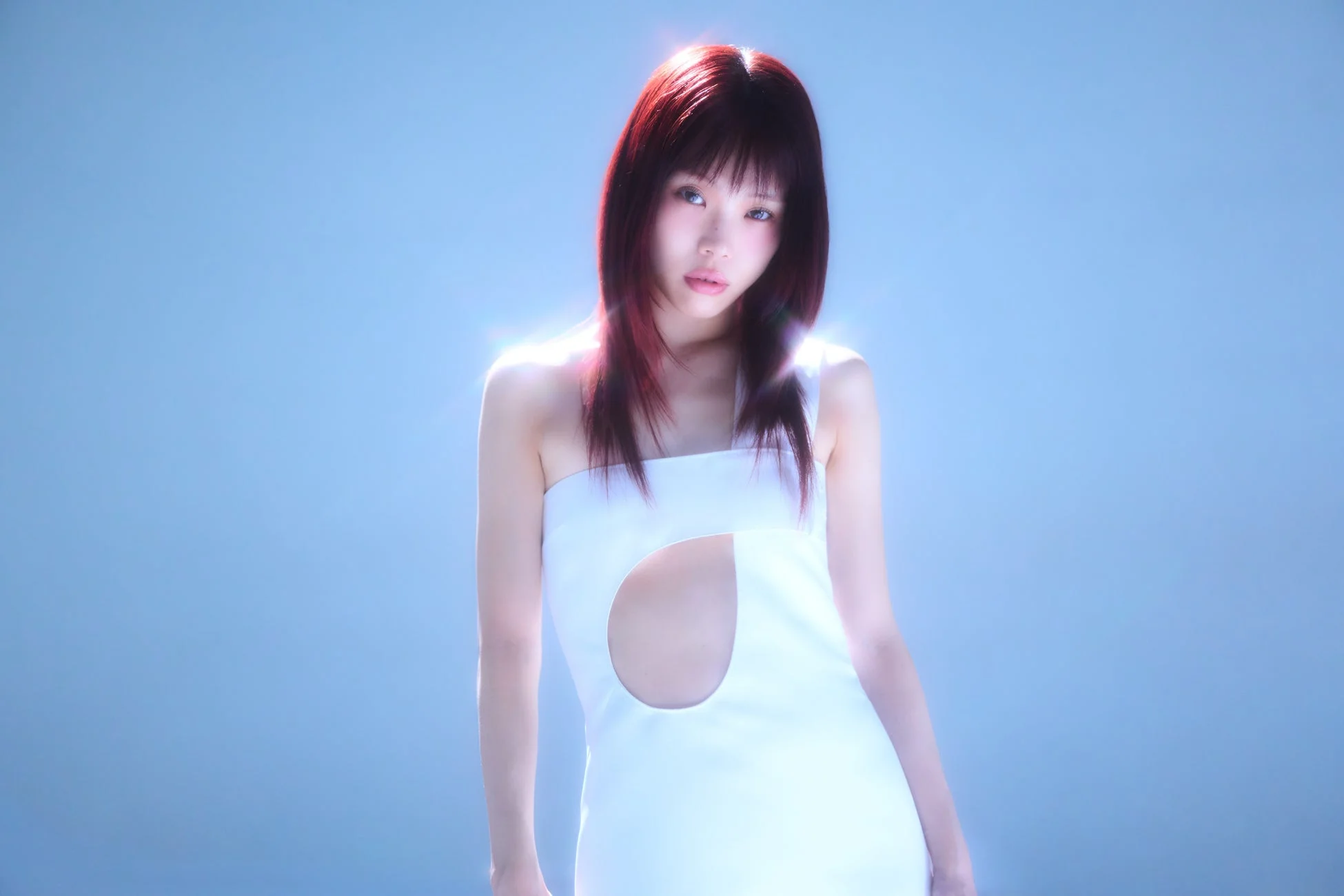 赤い髪の若い女性が白いストラップレスのカットアウトドレスを着用