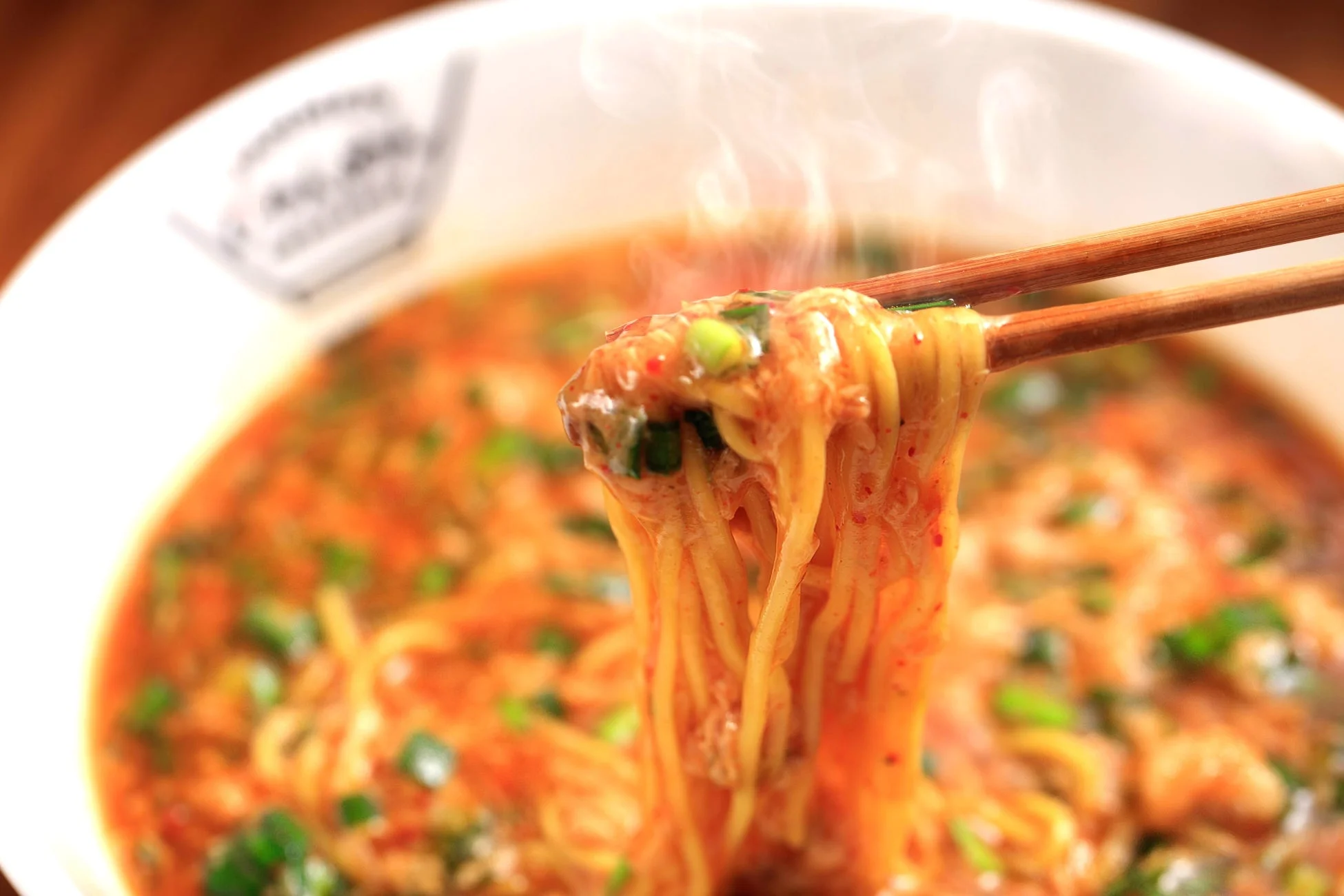 熱々の辛そうなラーメンを箸で持ち上げる様子