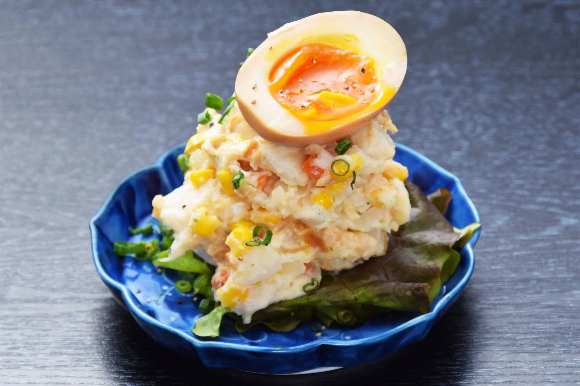青い器に盛られたポテトサラダで、半熟卵がトッピングされています。