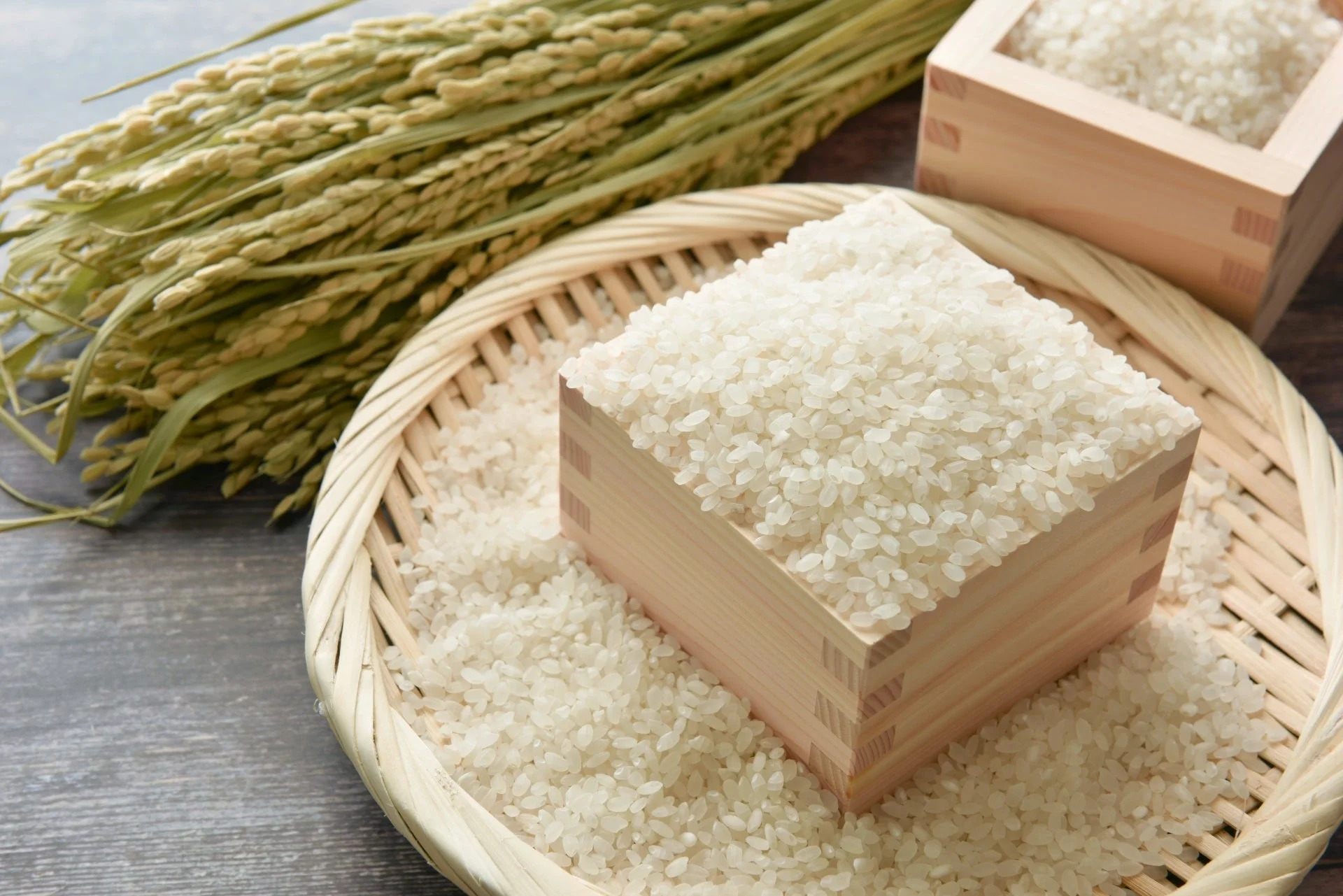 収穫されたばかりの稲穂と、木製の枡からあふれるように盛られた白米