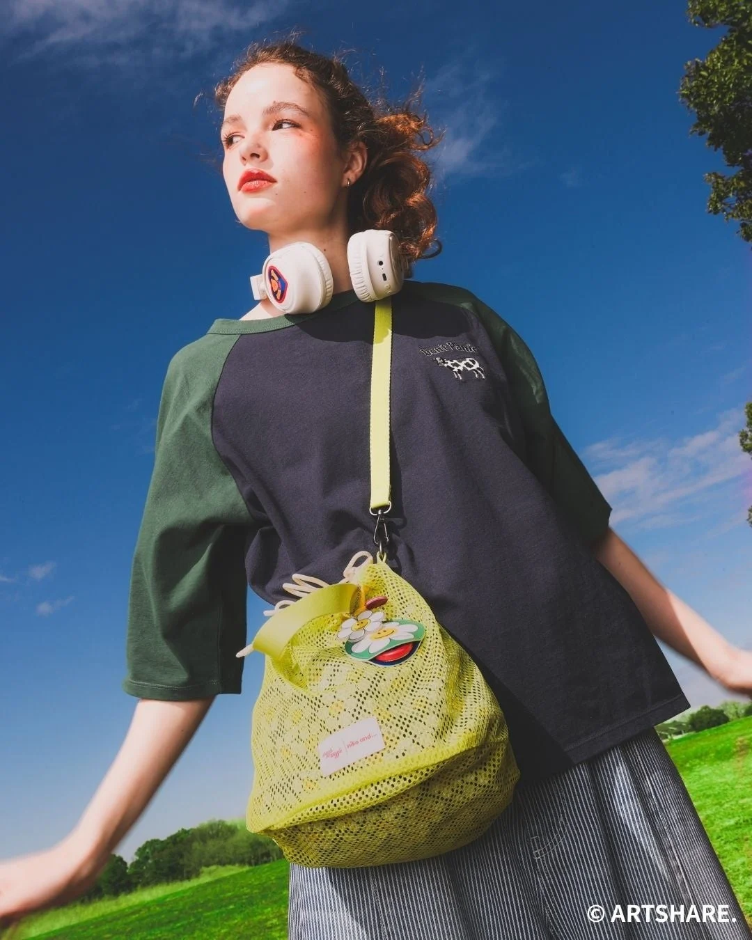 ラグランTシャツ、2WAYショルダーバッグ、ワイヤレスヘッドホンを着用したモデル