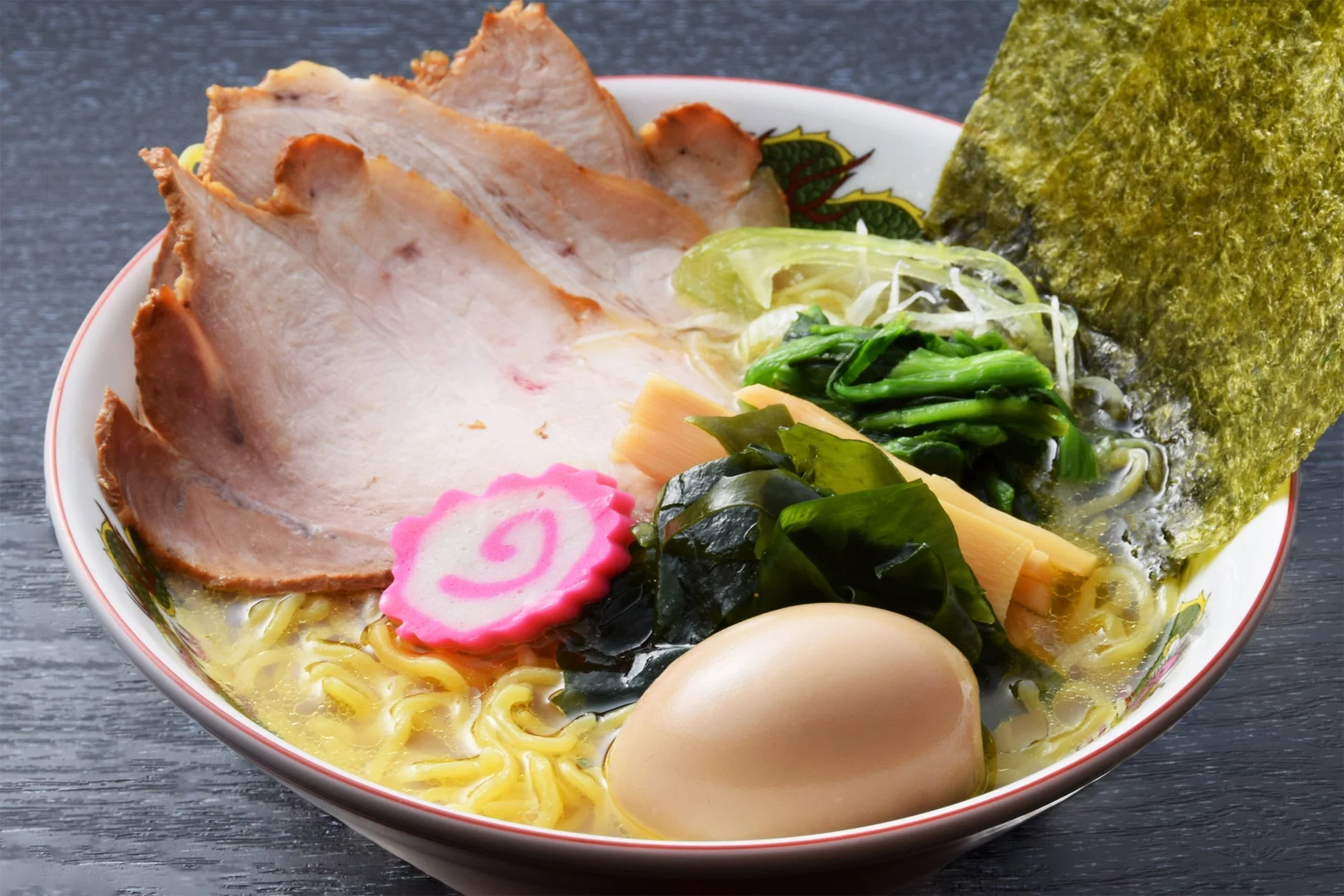 チャーシュー、煮卵、海苔、わかめ、なるとなど豊富な具材が盛り付けられた、食欲をそそるラーメン