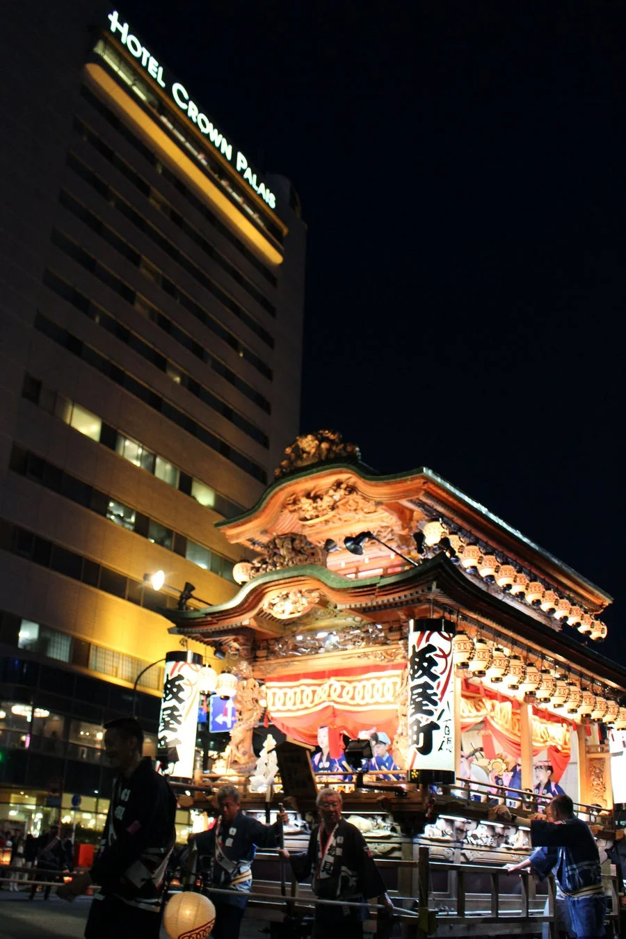 夜の街で豪華な山車が曳かれている様子