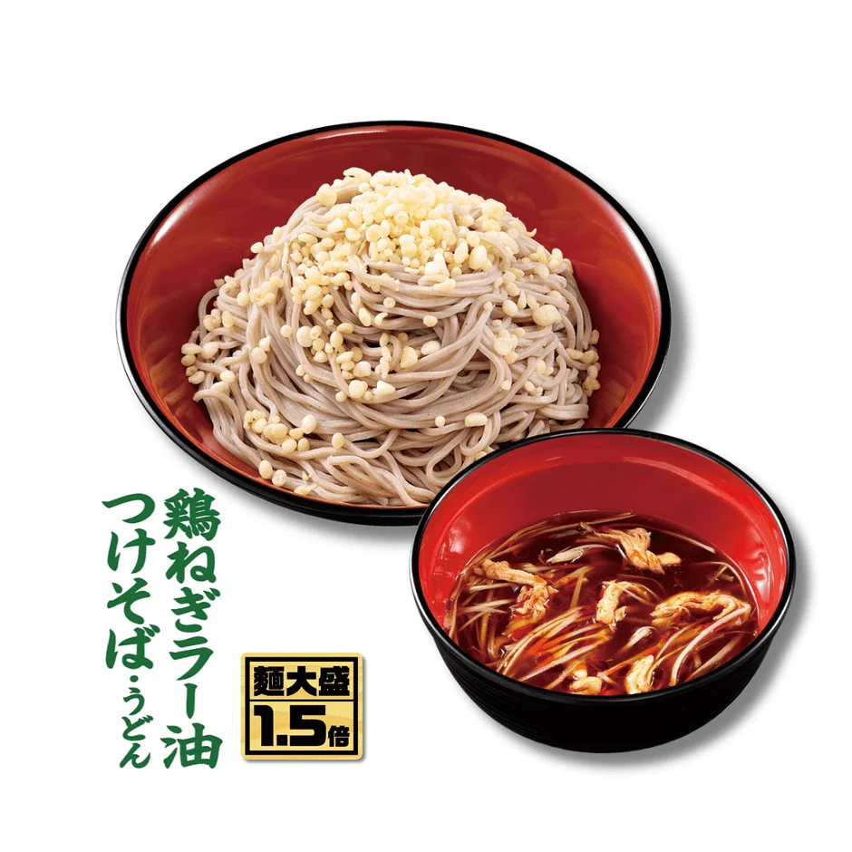 鶏とねぎ、ラー油が効いたつけ汁で食べるつけそば・うどんの画像です。麺は天かすが乗った大盛りで、通常より1.5倍の量があることを示しています。