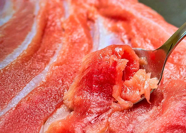 新鮮なマグロの中落ちをスプーンで削ぎ落としている様子