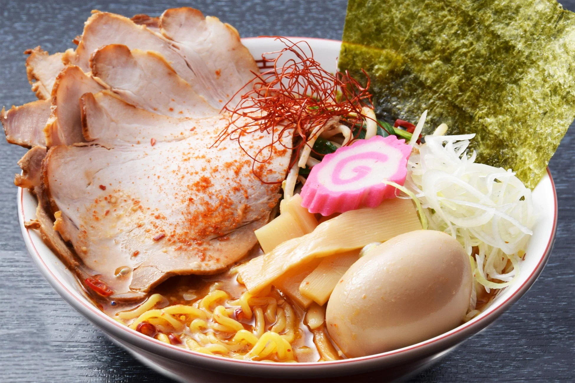 チャーシュー、味玉、メンマ、海苔、ネギなどが豊富に盛り付けられた、食欲をそそる温かいラーメン