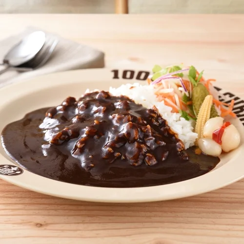 木製のテーブルに置かれたクリーム色の皿に盛られたカレーライス