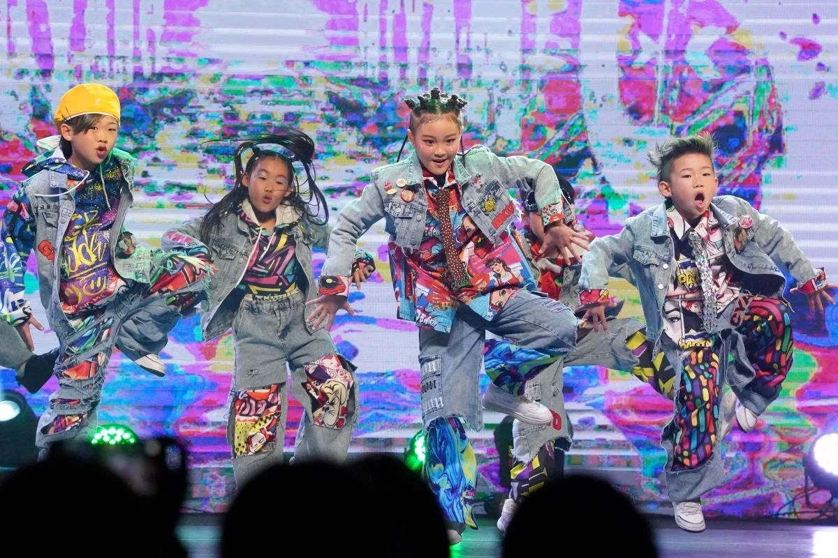 カラフルな衣装の子供たちがステージでダンスを披露している