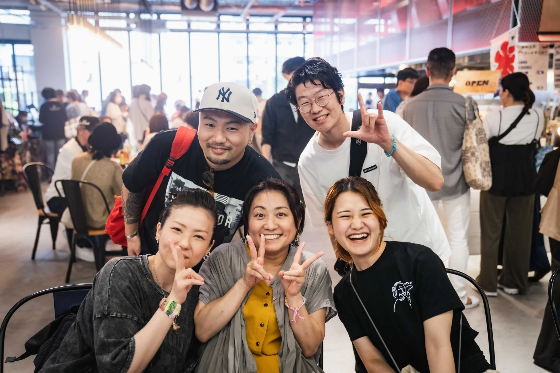 明るい屋内で、友人らしき男女6人が笑顔でポーズを取りながらカメラを見ている集合写真