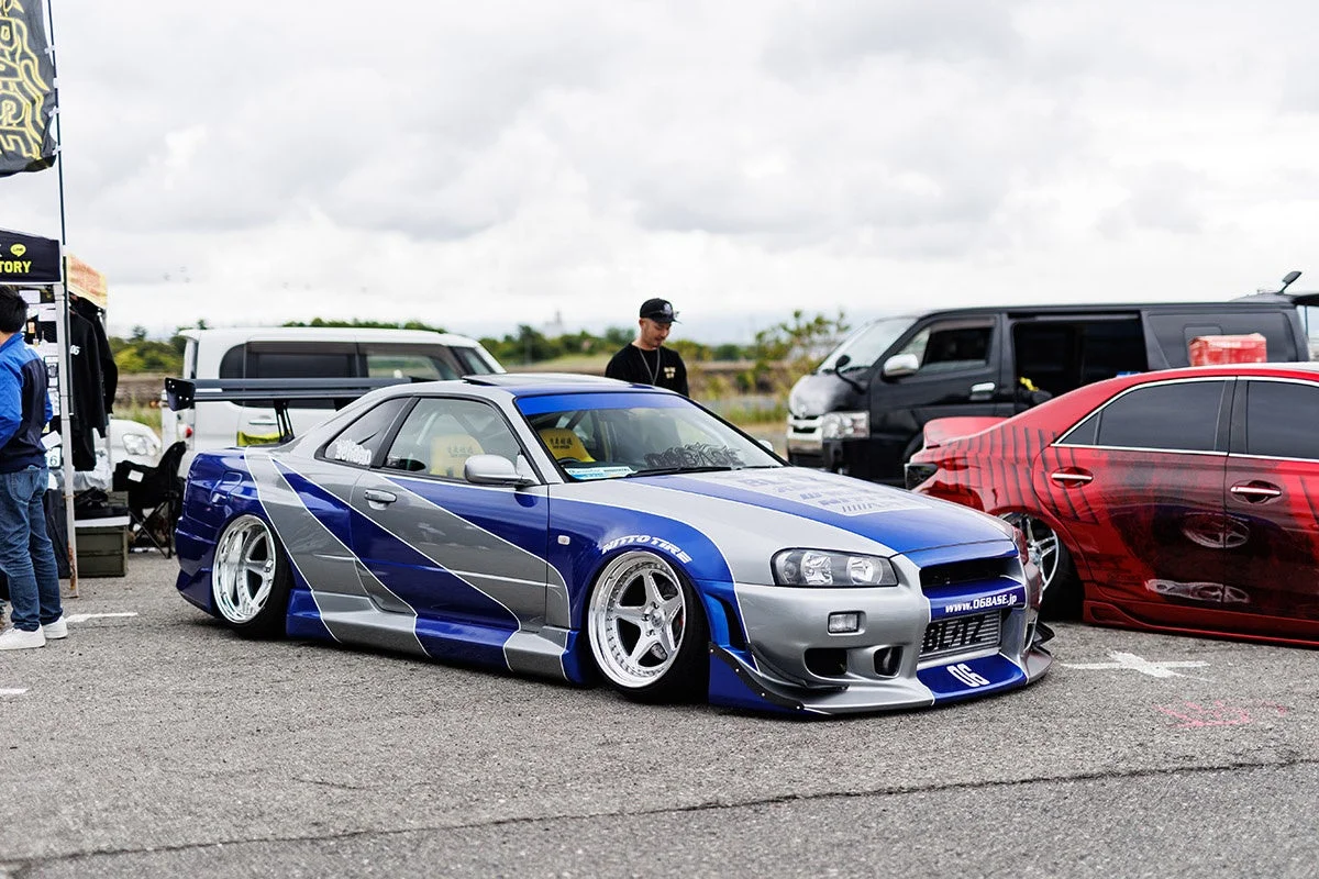 青とシルバーにカスタムされた日産スカイラインR34がメインの、屋外カーイベントの様子