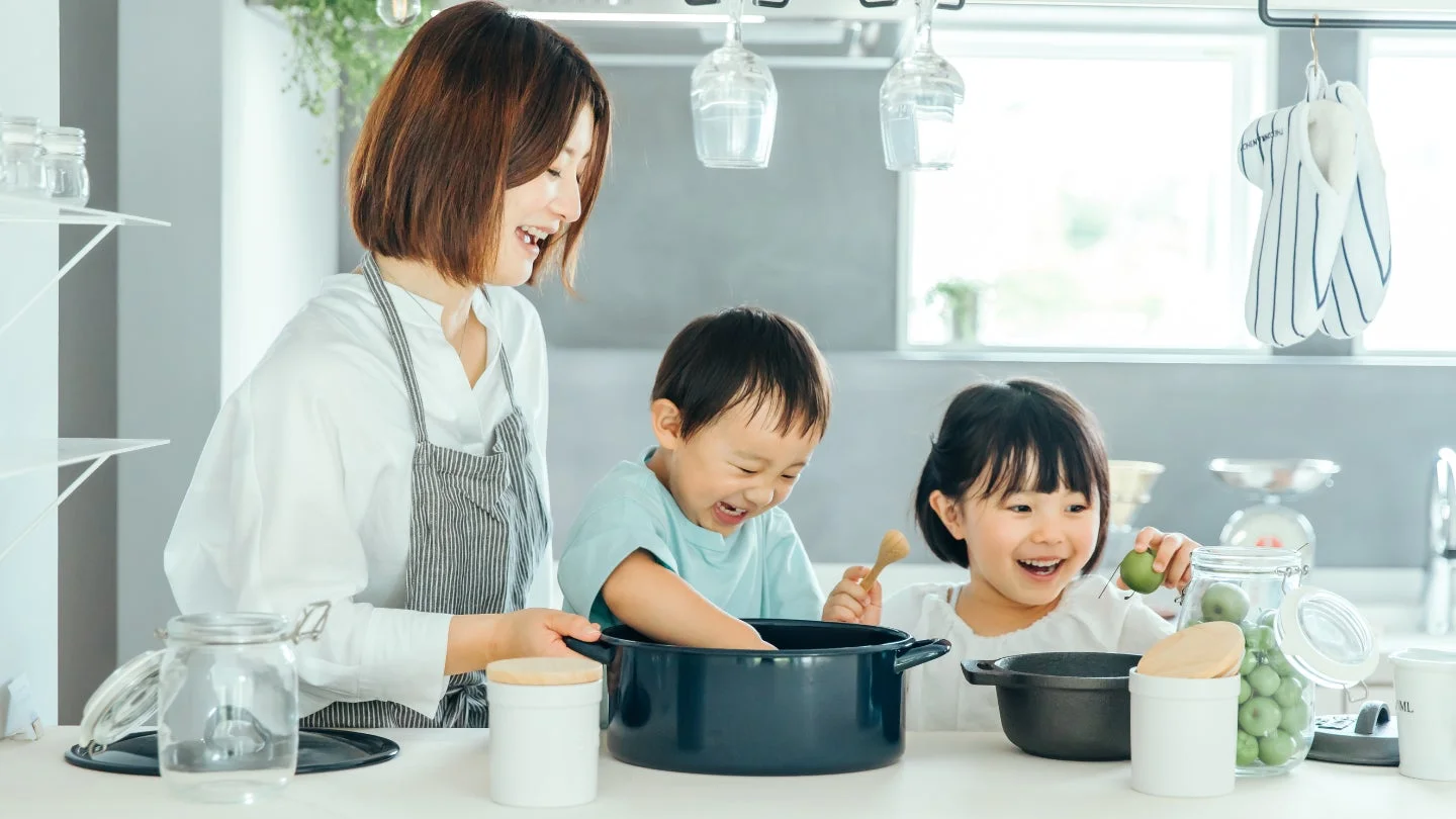 明るいキッチンで、母親と2人の子供が一緒に料理を楽しんでいる様子