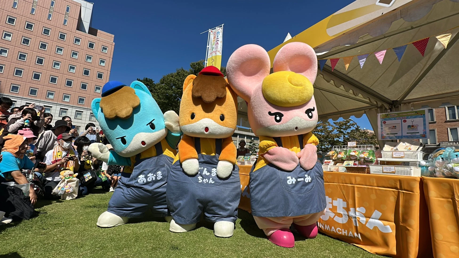 ぐんまちゃん、あおま、みーみがポーズをとり、観客が写真撮影