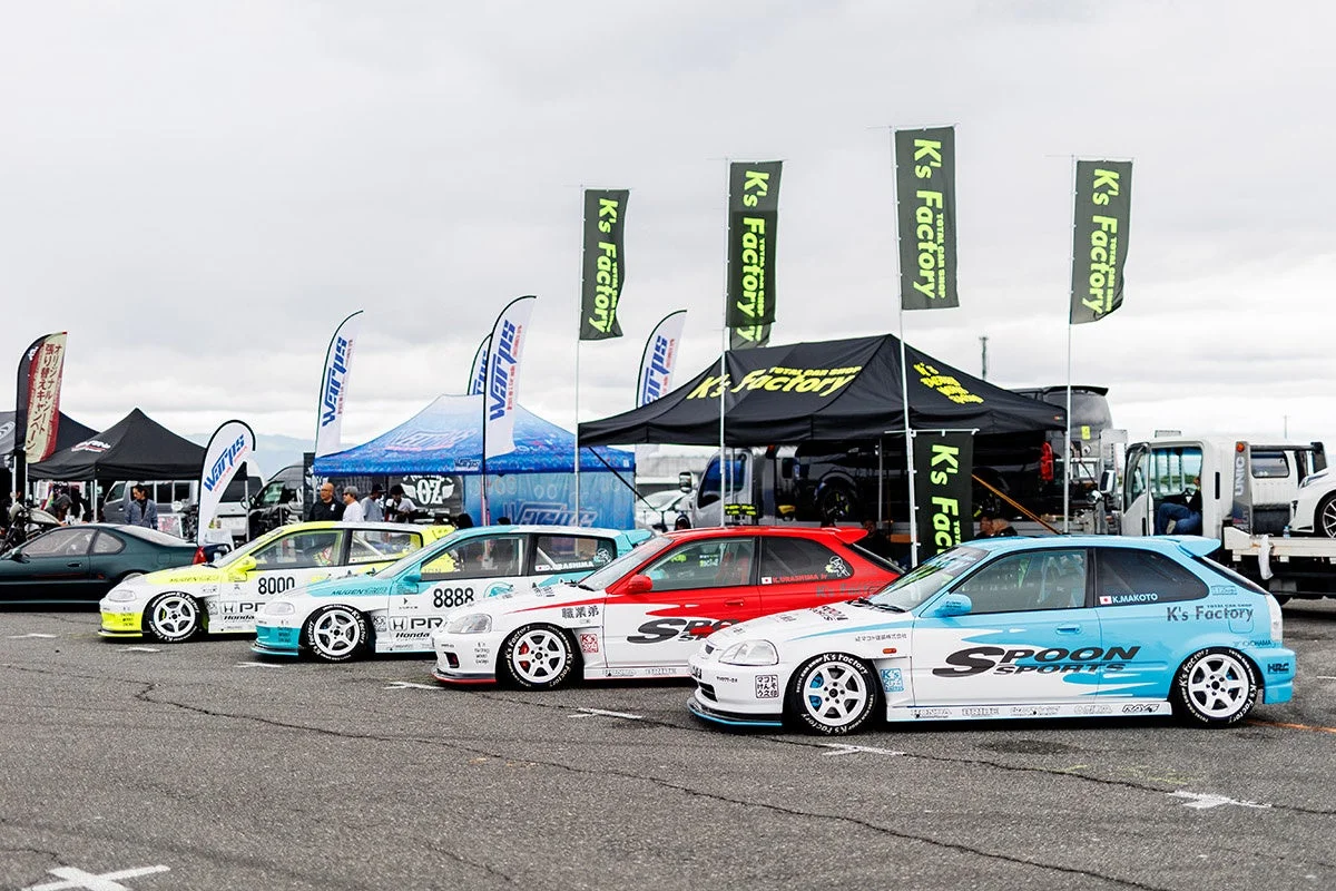 複数のホンダ・シビックのレースカーが、モータースポーツイベントのパドックらしき場所に並べられています