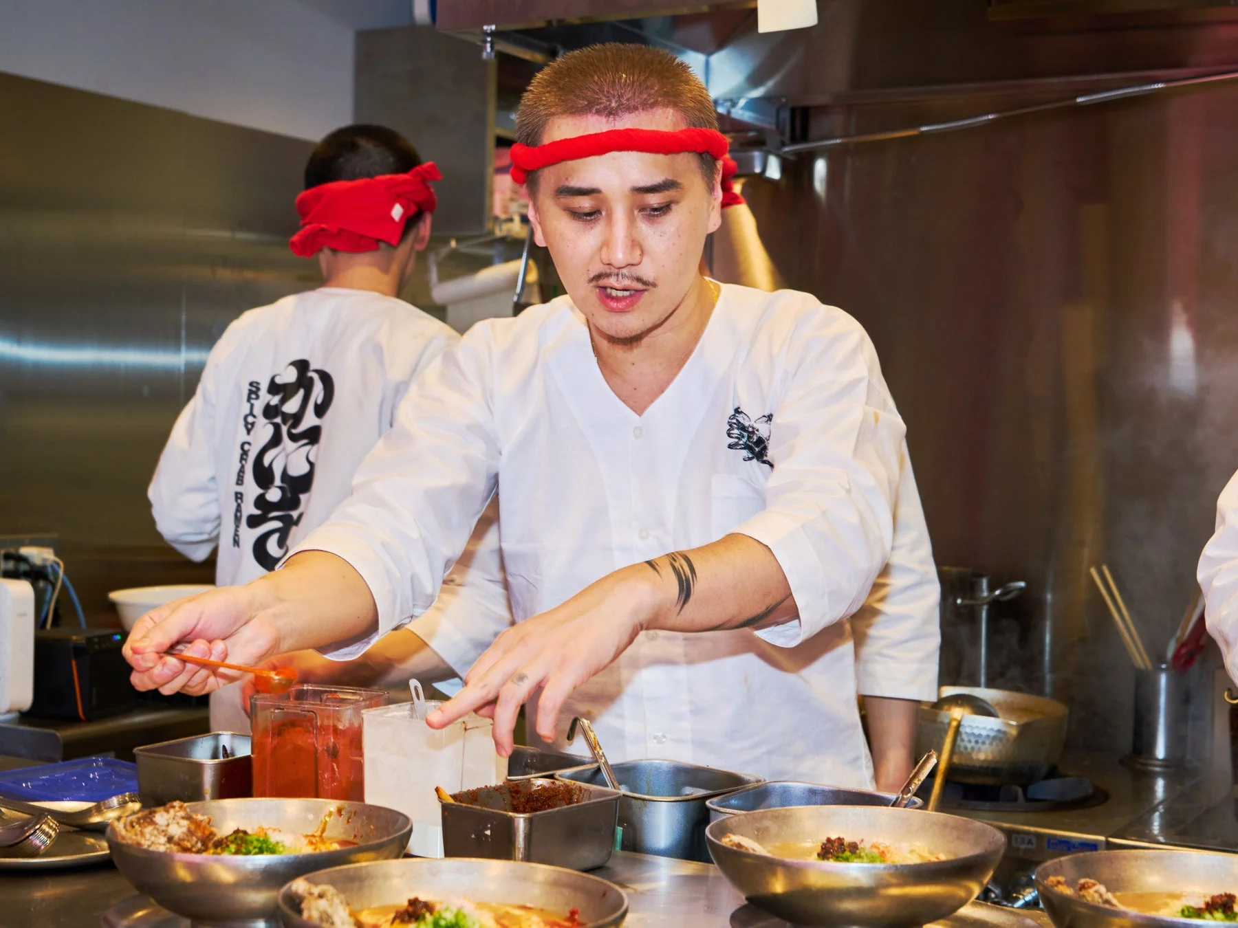 厨房でラーメンを盛り付けるこめおさん