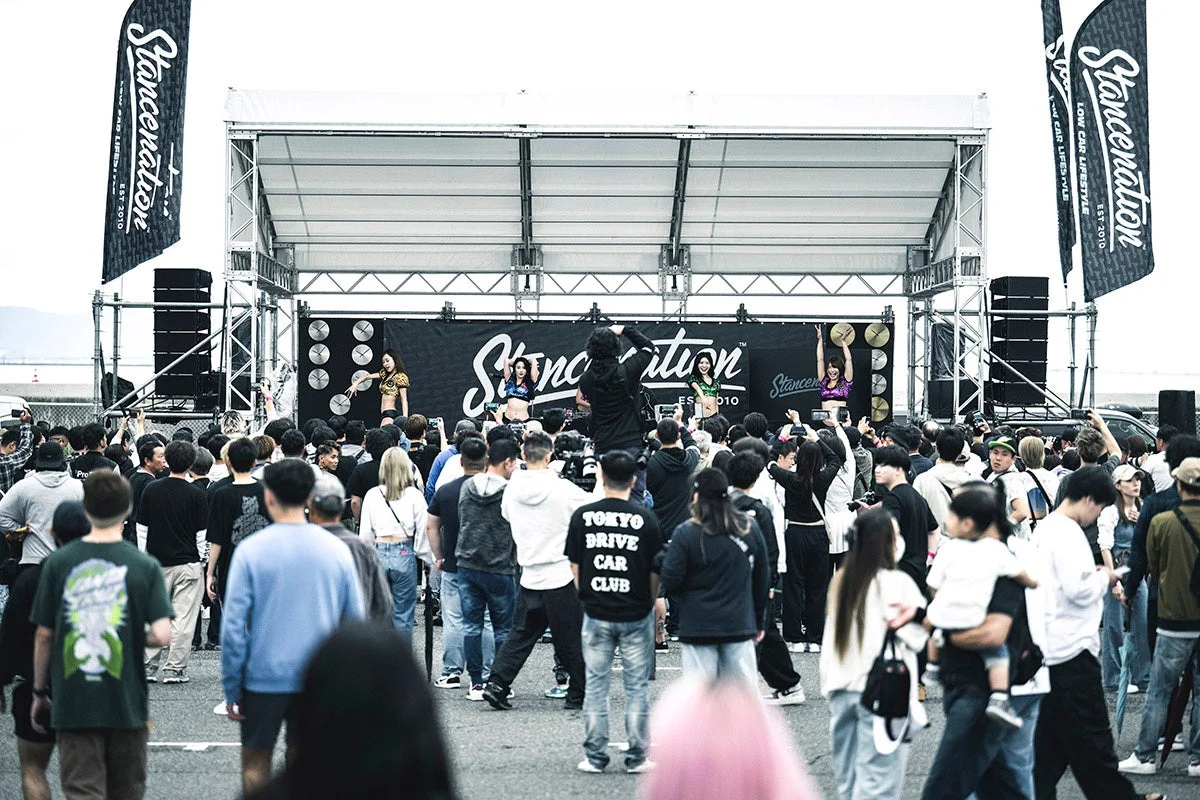 屋外の「Stancenation」イベント会場で、ステージ上の女性パフォーマーが観客の前でパフォーマンスを披露