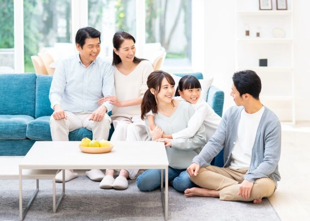 広々としたリビングで、三世代の家族が笑顔で和やかに過ごしている様子