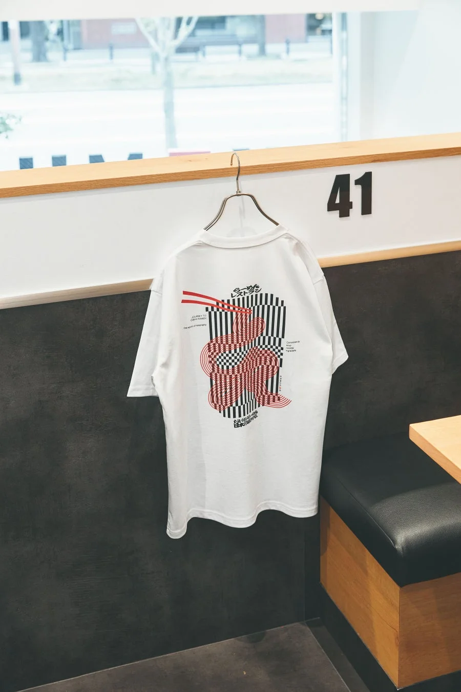 ラーメンをテーマにしたグラフィックデザインの白いTシャツ