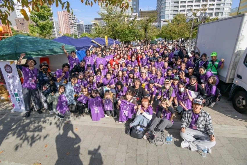 紫色のTシャツを着たボランティアスタッフの集合写真