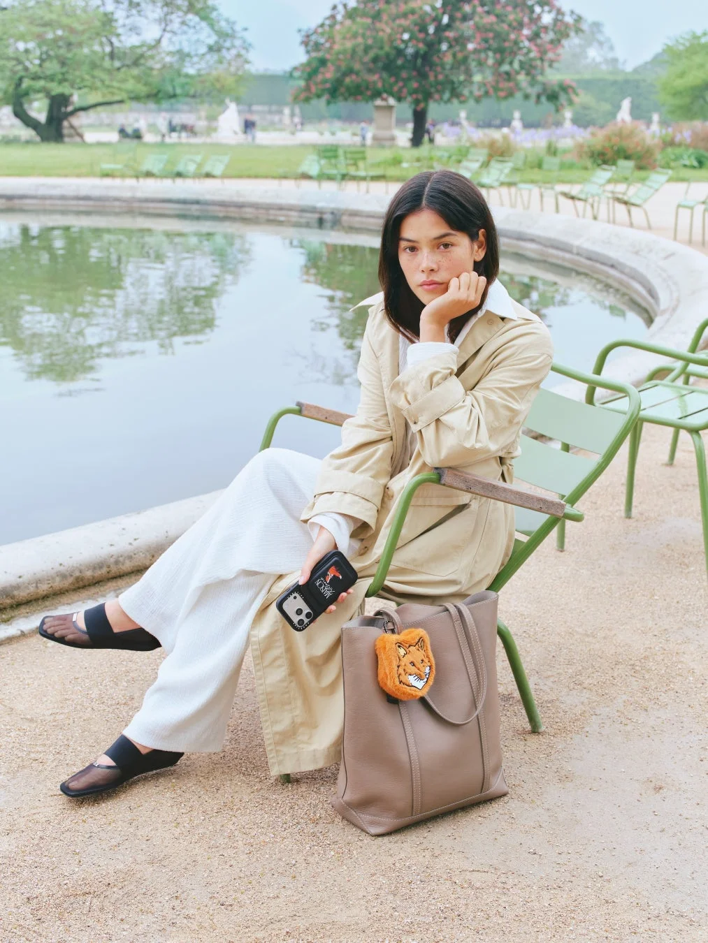 Maison Kitsunéのチャーム付きトートバッグを持つ女性