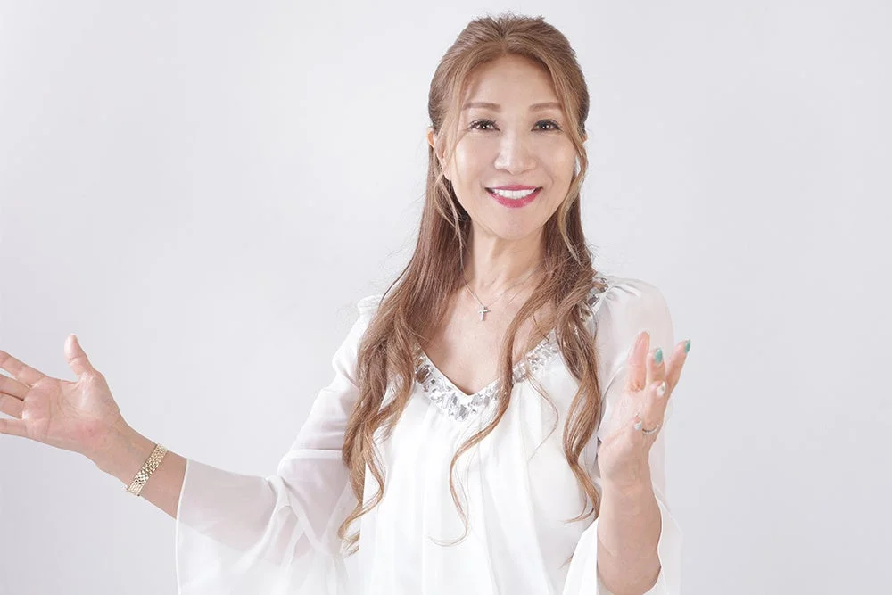白い背景の前で笑顔で両手を広げるアジア人女性のポートレート