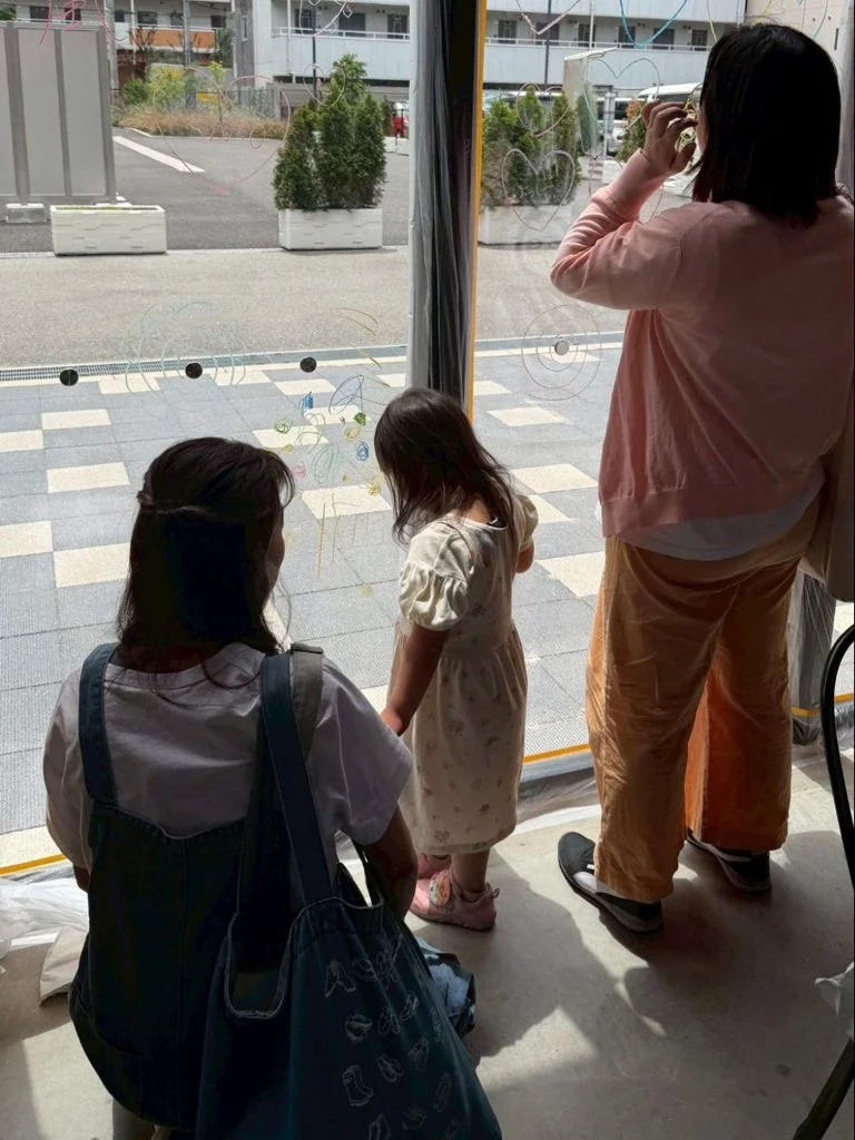 窓に自由に絵を描く子どもと大人