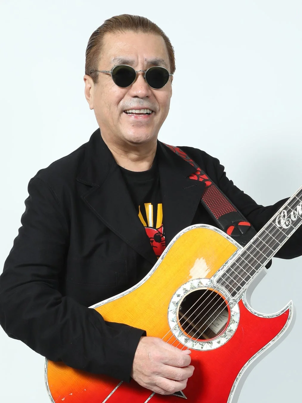 ギターを抱え笑顔の嘉門タツオさん