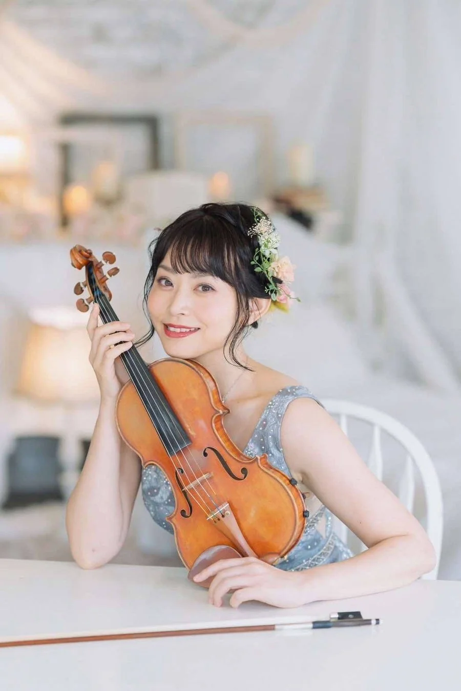 バイオリンを抱え、カメラに向かって優しく微笑む若い女性