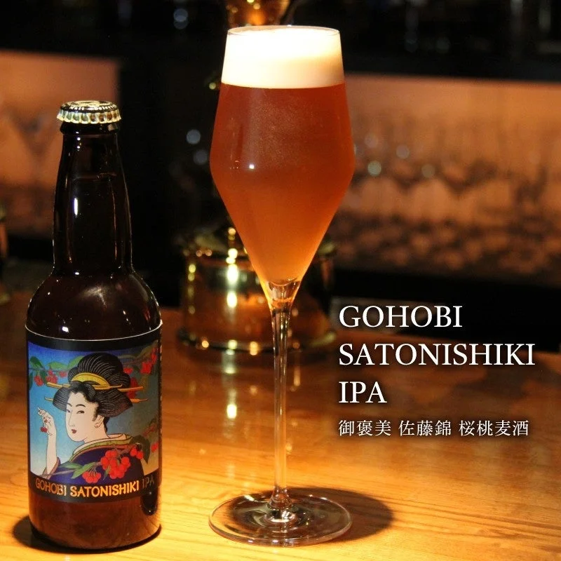 「GOHOBI SATONISHIKI IPA」のボトルとグラスが写るクラフトビールの画像です。ボトルには和風の女性イラストが描かれ、バーカウンターのような場所で泡立つビールが美味しそうに注がれています。