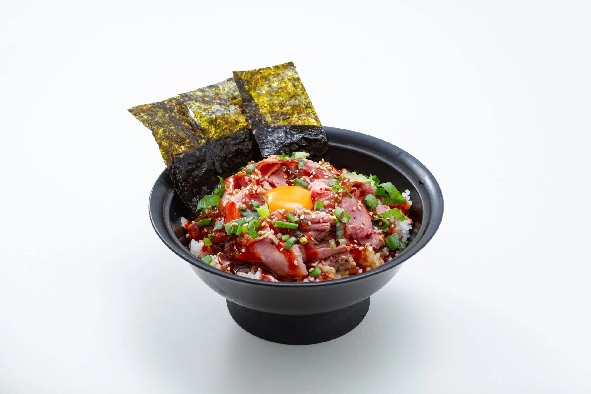 ご飯の上に薄切りローストビーフ、卵黄、刻みネギ、海苔が盛り付けられた丼