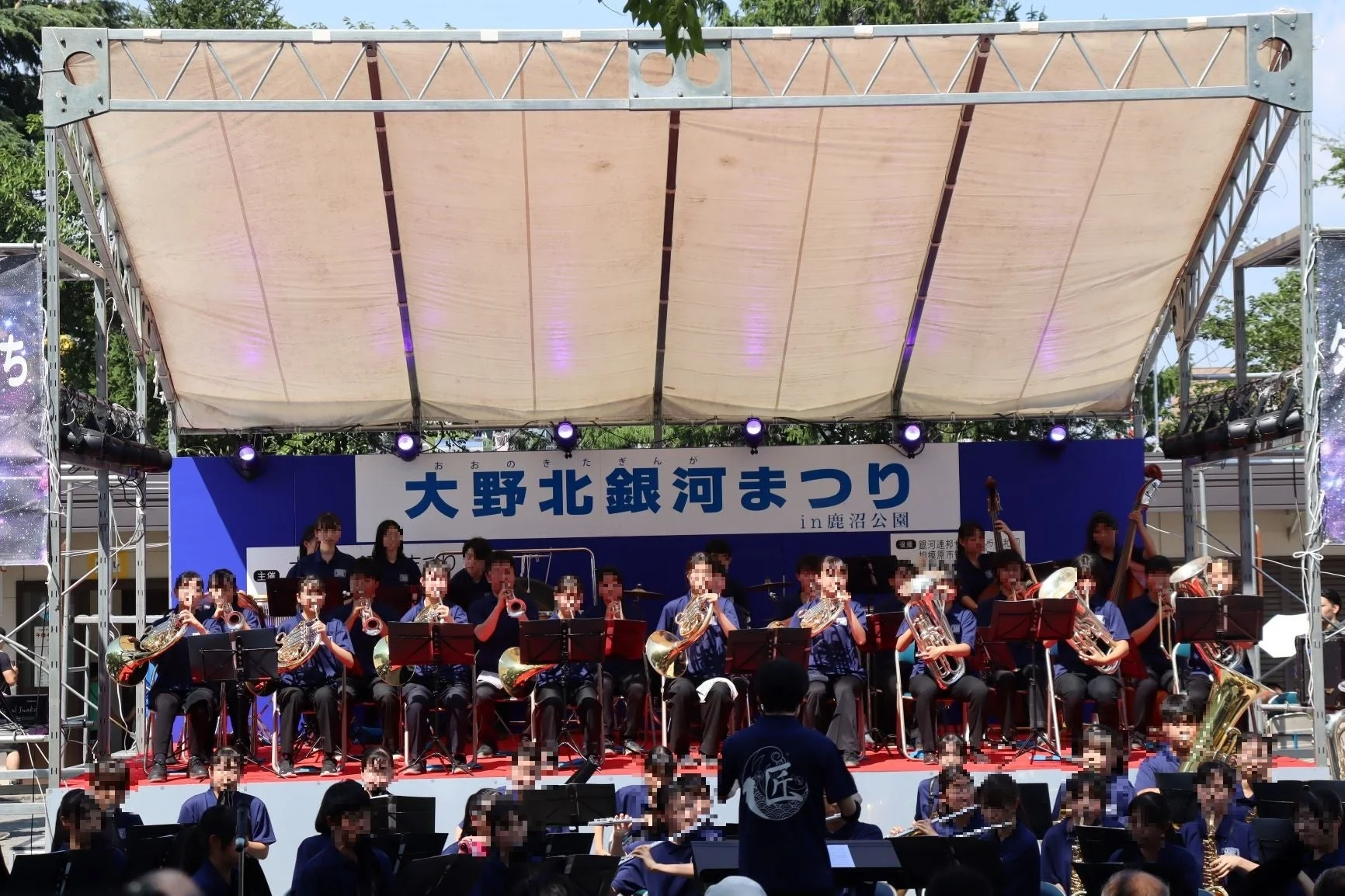 晴天下の屋外ステージで演奏する吹奏楽団