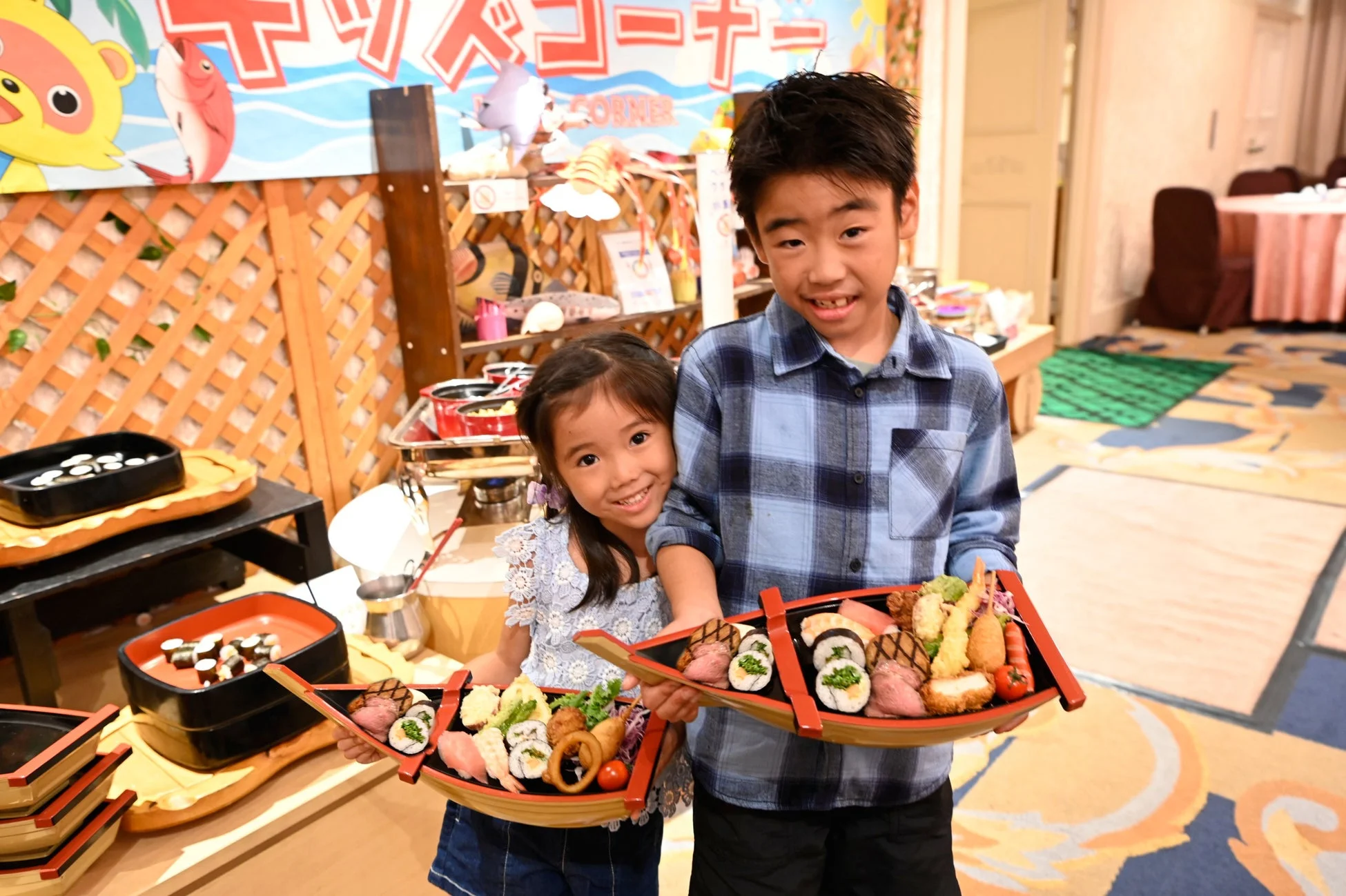 キッズコーナーで船盛りの寿司や天ぷらを持つ子どもたち