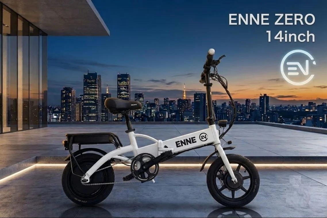 白い折りたたみ電動自転車「ENNE ZERO 14inch」が、都市の夜景を背景にしたモダンな屋上テラスに置かれている。スタイリッシュなデザインで都市生活に溶け込む乗り物。