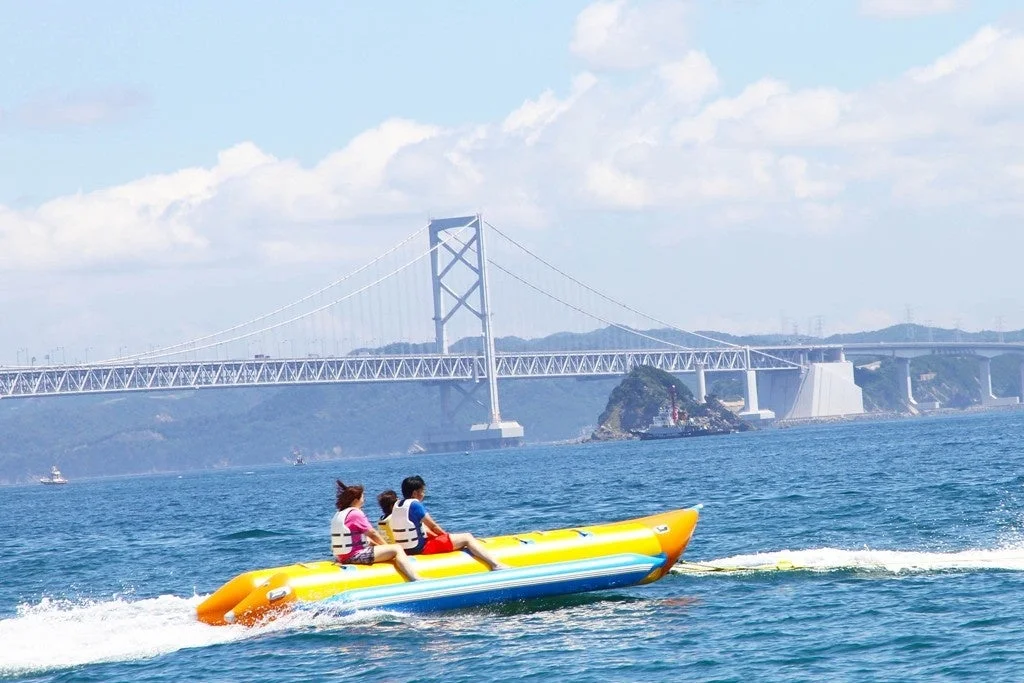 晴れた日に海でバナナボートを楽しむ人々