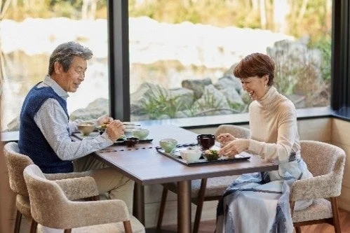 窓際の席で食事を楽しむ高齢の夫婦