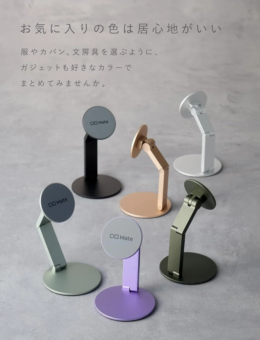 様々なカラーバリエーションの「OO Mate」ブランドのスマートフォンスタンドが並べられています。服や文房具を選ぶように、好みの色でガジェット周りを統一し、居心地の良い空間を作ることを提案する広告画像です。