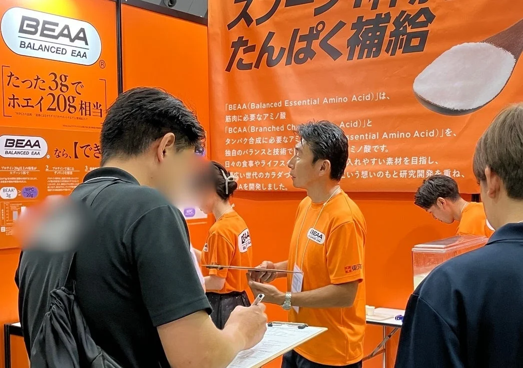 健康食品のプロモーションブースで来場者とスタッフが交流している様子