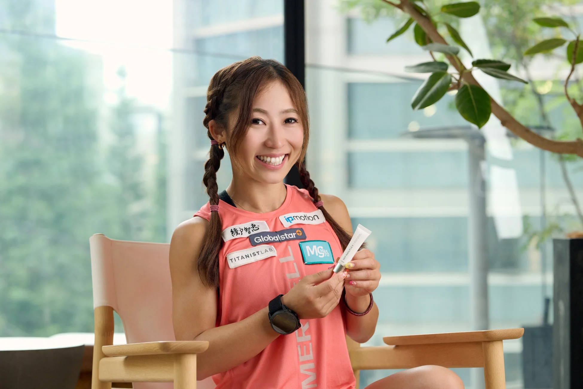 笑顔の女性がスポーツウェアを着て、健康関連の製品と思われる白いチューブを手にしている