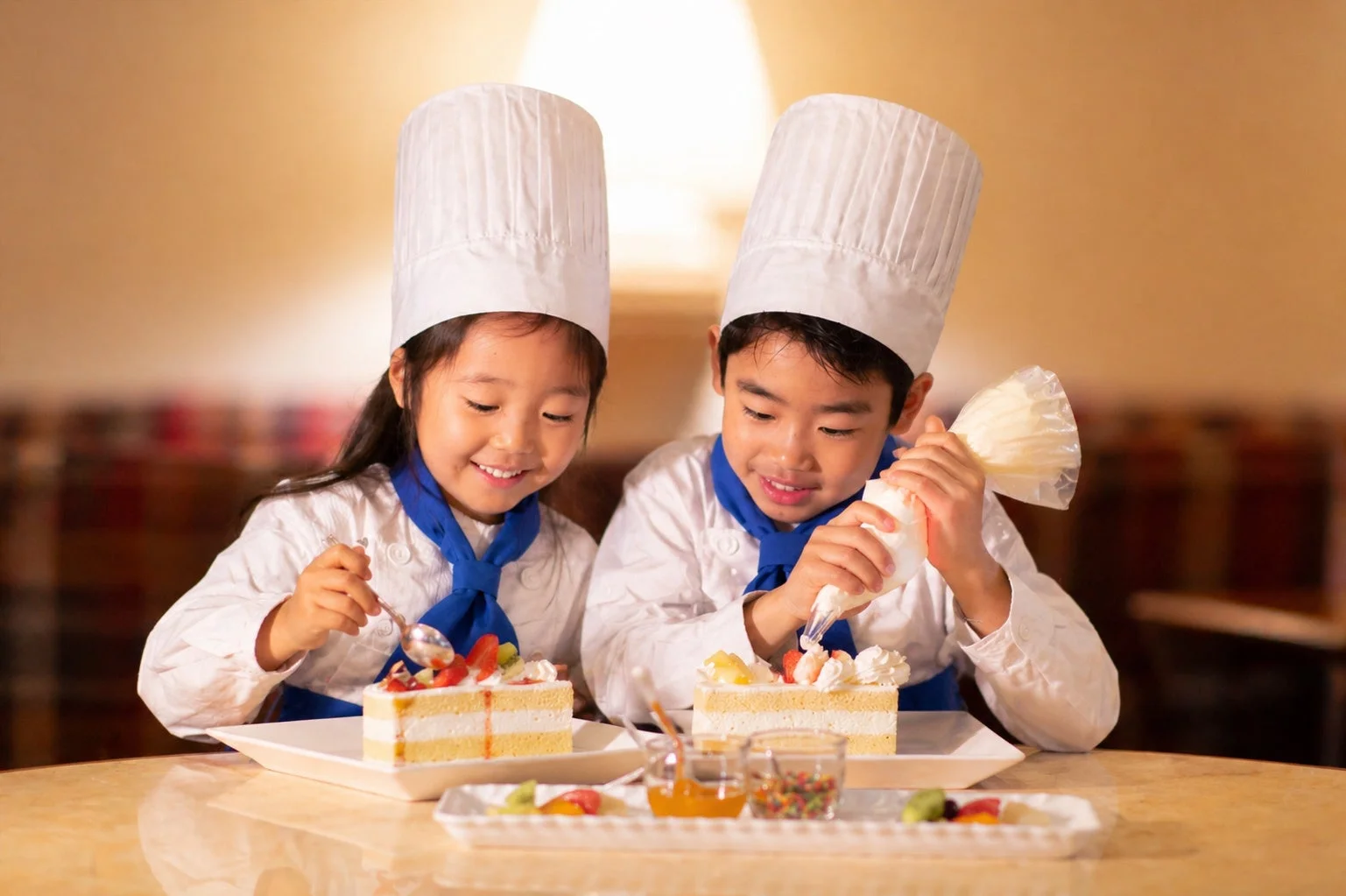 シェフの衣装を着てケーキのデコレーションを楽しむ子供たち