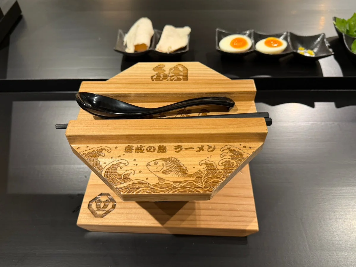 壱岐の島ラーメンと鯛のイラストが彫られた木製の器
