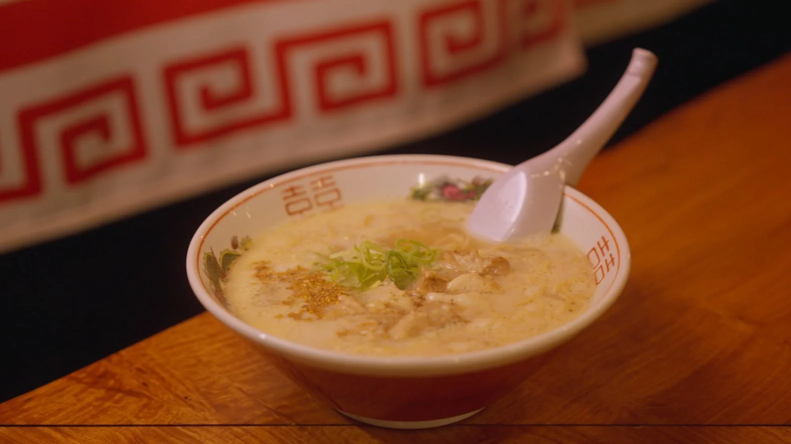 木製のテーブルに置かれたクリーミーなスープの麺料理