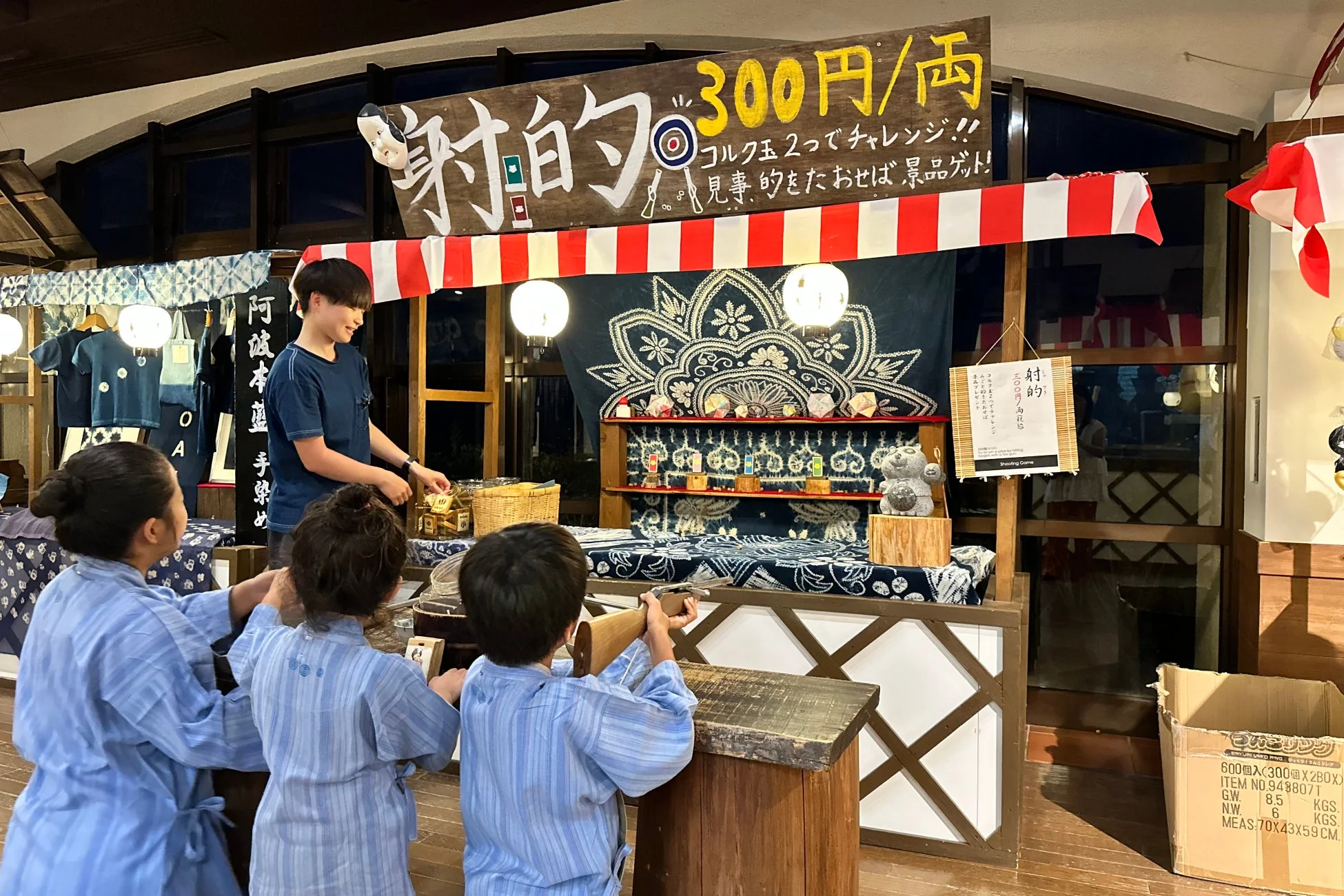 浴衣のような装いで射的ゲームを楽しむ子供たち