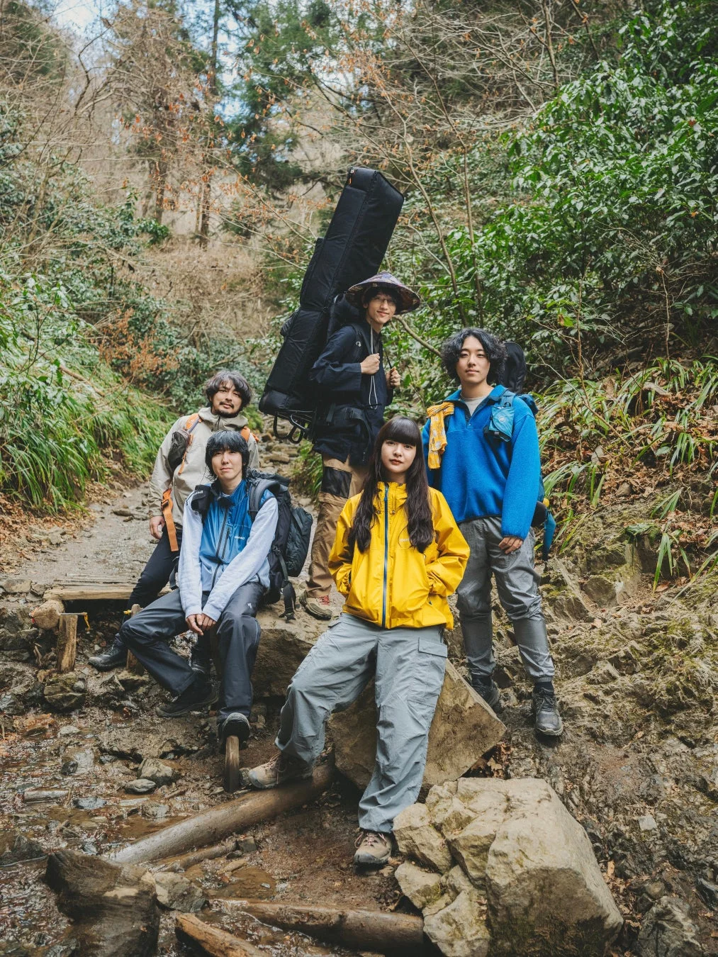 森の中の岩や泥の多い道を歩くスーパー登山部のメンバー