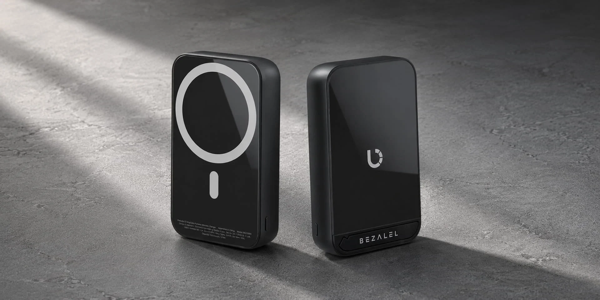 MagSafe対応の黒いワイヤレス充電モバイルバッテリー2台が、質感のあるグレーの背景に置かれています。洗練されたデザインで、「BEZALEL」のブランド名とロゴが確認できます。
