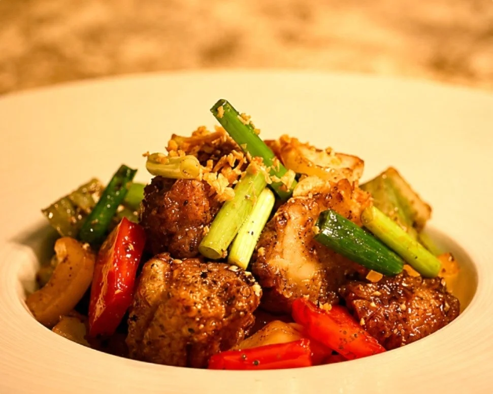 鶏肉(または豚肉)と彩り豊かな野菜が炒められた一皿。香ばしい揚げネギが添えられている